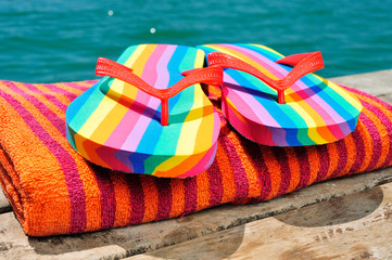 rainbow flip-flops and towel on a dock