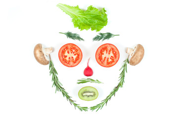 Funny face from different vegetables tomatoes, cucumber, radish, dill and rosemary isolated on white background. Healthy eating and vegan food concept. Kitchen