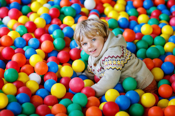 Fototapeta na wymiar Little kid boy playing at colorful plastic balls playground