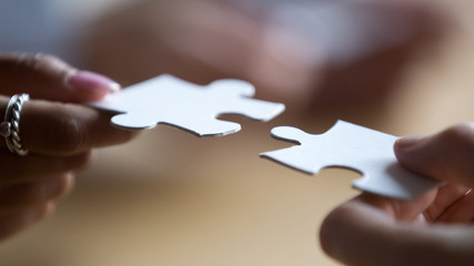 Close up multiracial business team members connecting puzzle pieces