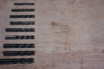 Drill bits, screwdriver assortment on a wooden background