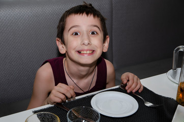 A little boy with Cutlery waiting for the meal