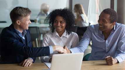 Confident businessman shaking hand of African American business partner