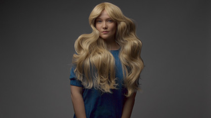 nordic blond model in studio with dramatic top light. jumping and showing gorgeous hair curls