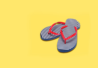 Vacation season - the concept. Beach flip flops on a yellow background.