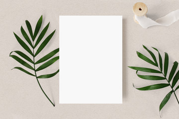 Feminine wedding stationery mock-up scene. Blank greeting card, green palm leaves and silk ribbon...