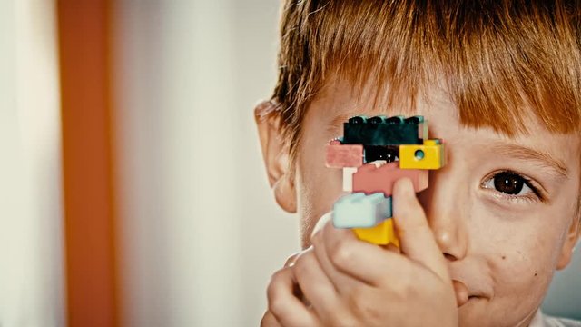 Child looking through scope from plastic bricks