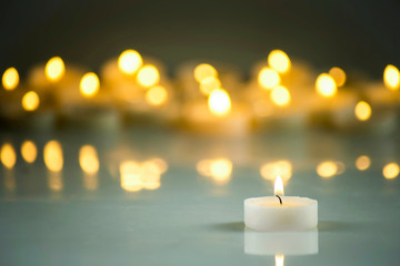Obraz na płótnie Canvas A lit white candle on a background of blurred lights