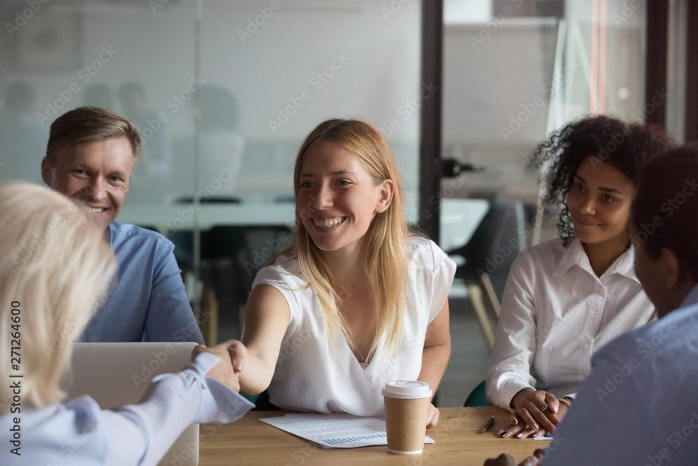 Poster Attractive businesswoman shaking hand of business partner at meeting