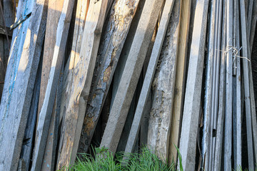 Old boards and wooden slats stand against the wall of the house on the grass