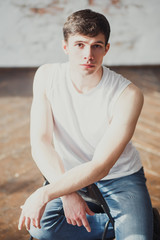 portrait of a young man in jeans and a sleeveless jacket