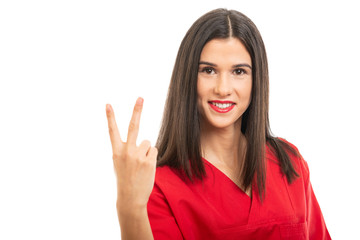 Portrait of beautiful nurse wearing red scrubs showing number two gesture