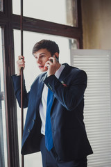 a young man in a classic suit talking on the phone