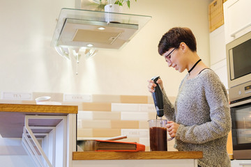 The girl is mixing a chocolate dough for baking with a mixer. Portrait of woman cooking dessert.