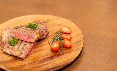 Fresh cooked half cut beef sirloin with cherry tomato and rosemary on top with parsley, Wood background