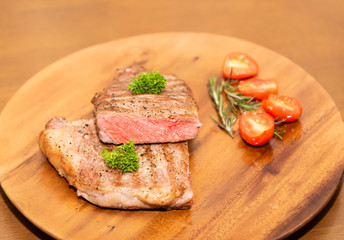 Fresh cooked half cut beef sirloin with cherry tomato and rosemary on top with parsley, Wood background