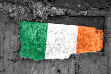 The flag of Ireland on a dirty wooden surface, built into a concrete base, with scuffs and...