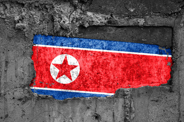 The flag of North Korea on a dirty wooden surface, built into a concrete base, with scuffs and...