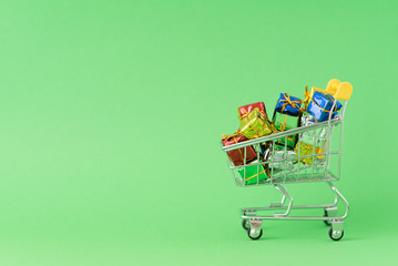 Christmas gifts in supermarket trolley on green background. Online shopping concept - trolley full of gifts. Black Friday and Cyber Monday