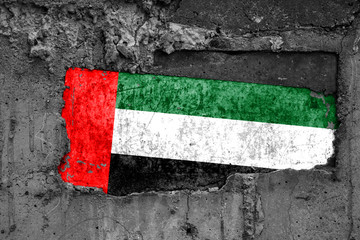 The flag of United Arab Emirates on a dirty wooden surface, built into a concrete base, with scuffs...