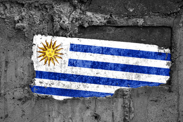 The flag of Uruguay on a dirty wooden surface, built into a concrete base, with scuffs and...