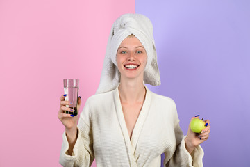 Healthy girl with apple and water glass. Weight loss. Healthy lifestyle, diet, healthy food. Happy woman holds in hands fresh green apple and glass of water. Cheerful lady holds fruit and beverage.