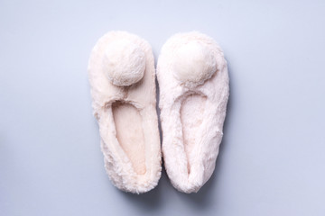 Nude fluffy home slippers with pompon on pastel grey background. Top view. Copy space. Cozy home footwear. Sweet home and spa, body treatment concept - obrazy, fototapety, plakaty