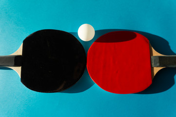 Table tennis bats and ball on blue copy space