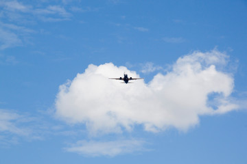 plane flying in the sky over some clouds in a sunny day