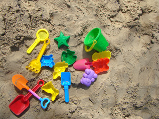 Fototapeta na wymiar Multi-colored toys on the sand. Sunny day at the beach