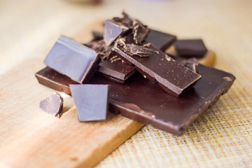 Cut chocolate pieces on the wooden background