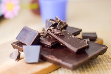 Cut chocolate pieces on the wooden background