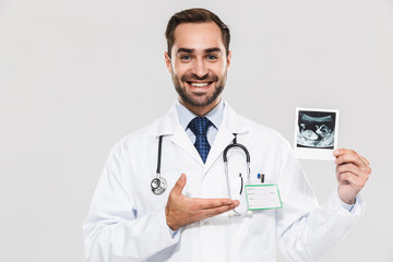 Portrait of caucasian young medical doctor working in hospital and holding ultrasound scan of baby
