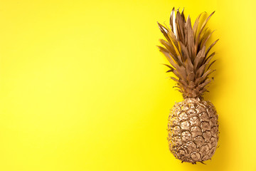 Creative layout. Gold pineapple on yellow background with copy space. Top view. Tropical flat lay. Exotic food concept, crazy trend. Banner