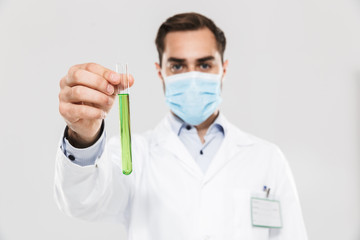 Portrait of professional young medical doctor working in clinic laboratory and holding test tube