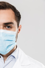 Portrait of brunette young medical doctor wearing sterile mask working in clinic laboratory and looking at camera