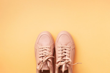 Woman fashion pink shoes on pink background with copy space. Top view. Flat lay. Fitness, sport concept. Nude female sneakers