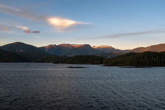 The view at sunset from the side of a ferry as it makes its way through the Inside Passage off the rugged west coast of Canada, the light fading behind the hills in the distance, nobody in the image