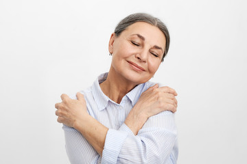 Self-love, joy and happiness concept. Portrait of happy joyful elderly mature lady with wrinkled...