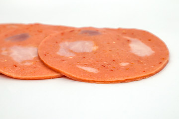 Bologna mixed with fresh chilli and pork ham, slides into a circular plate on a white background