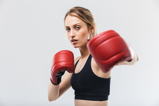 Image of athletic blond woman 20s dressed in sportswear and boxing gloves working out and during fitness in gym