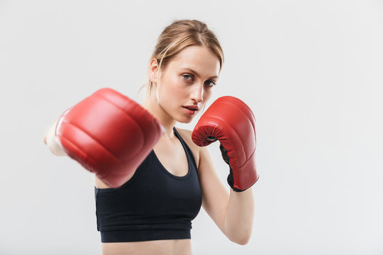 Image of healthy blond woman 20s dressed in sportswear and boxing gloves working out and during fitness in gym