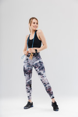 Full length image of fit blond woman 20s dressed in sportswear doing workout in gym with jumping rope