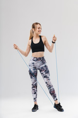 Full length image of slim blond woman 20s dressed in sportswear doing workout in gym with jumping...