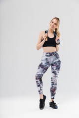 Full length image of fitness blond woman 20s dressed in sportswear doing workout in gym with jumping rope