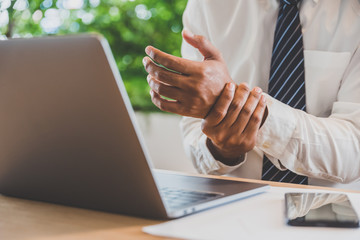 Businessman pain in hands while woking with laptop. Office syndrome concept.