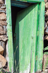 Old green, skew, wooden door at a stone shed, located on the hiking trail from the village El Cercado down the Argaga ravine to the Valle Gran Rey on the canary island La Gomera