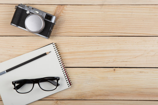 Writer, journalist or traveler desk - notepad and photo camera on the wooden background