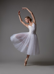 Ballerina dancing in white dress. Color photo.