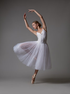 Fototapeta Ballerina dancing in white dress. Color photo.